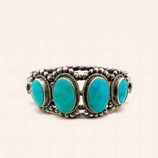 Silver cuff with turquoise stones on a beige background