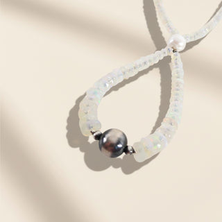 Necklace with white beads and a central black bead on a beige background