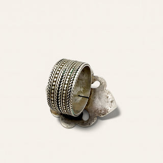 A vintage sterling silver ring holder with a wide, intricately patterned band and a smaller decorative accent piece, shown on a plain off-white background.