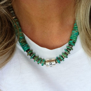 Close-up of a person wearing a green beaded necklace with a white background