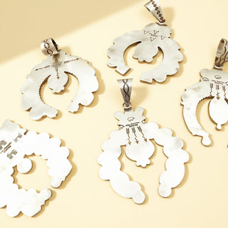 Five silver stamp pendants on a beige background