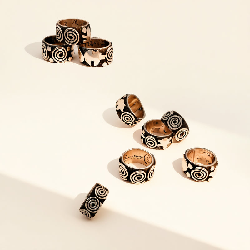 Set of black and gold spiral-patterned rings on a beige background