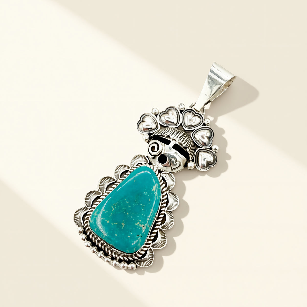 Silver pendant with a turquoise stone on a beige background