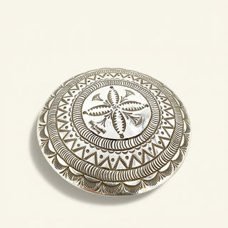 Decorative round metal object with intricate patterns on a beige background