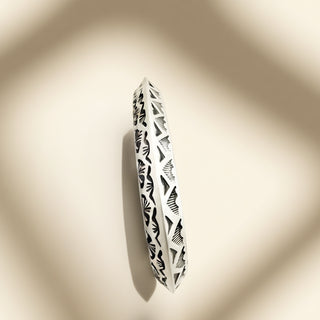Decorated silver cuff on a beige background