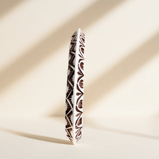 Silver cuff with designs on a beige background