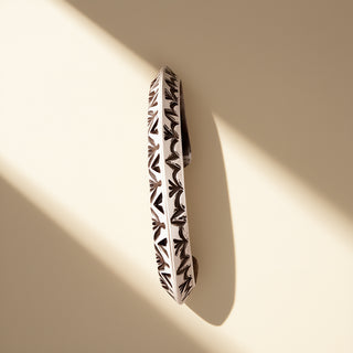 Silver cuff with designs on a beige background