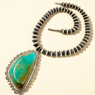 Necklace with turquoise pendant and black and black beaded chain on beige background