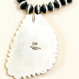 Necklace stamp displaying 'BK A. CADMAN' on a beige background