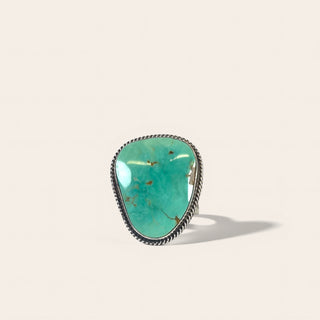 Turquoise ring with silver band on a beige background