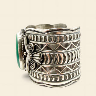 Silver cuff bracelet with geometric patterns on a beige background