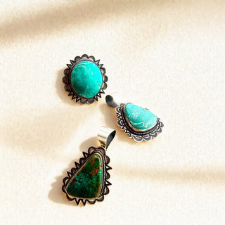 Three turquoise pendants against a beige background