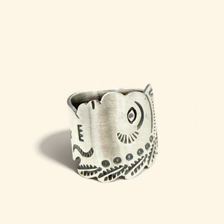 Silver ring with intricate designs on a beige background