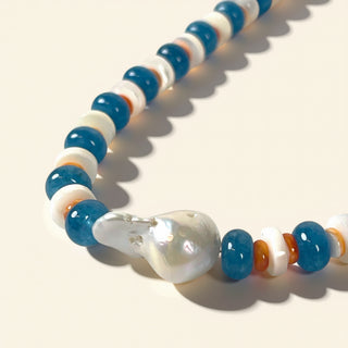 Necklace with blue, white, and orange beads on a beige background