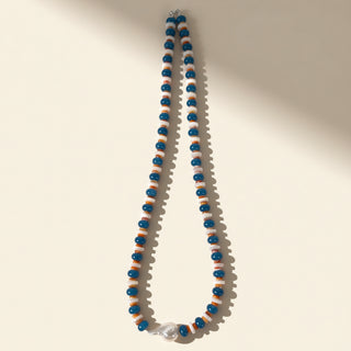 Necklace with blue and orange beads on a beige background