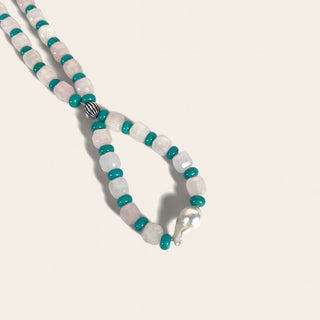 Necklace with white and turquoise beads on a light gray background