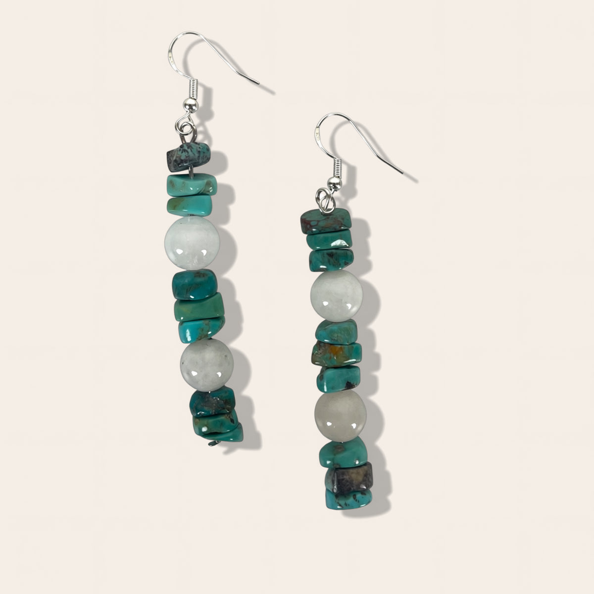 Pair of earrings with turquoise and white beads on a light gray background