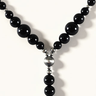 Necklace with black beads and silver accents on a white background