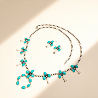 Turquoise jewelry set with necklace and earrings on a beige background