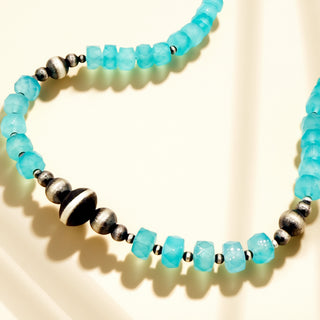 Necklace with turquoise beads and silver accents on a beige background