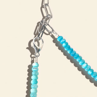 Turquoise beaded jewelry with silver clasp on a beige background