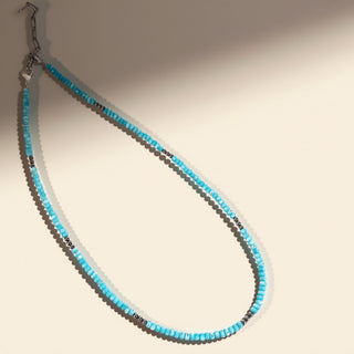 Necklace with blue and black beads on a neutral background