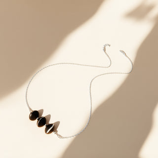 Necklace with three black pendant stones on a beige background