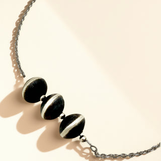 Necklace with black and silver beads on a beige background