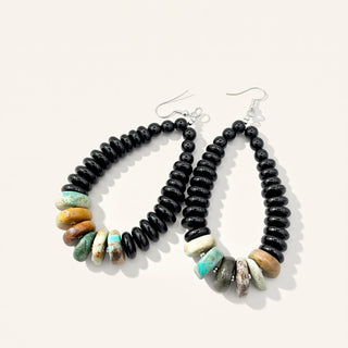 Beaded earrings with black, turquoise, and beige beads on a white background