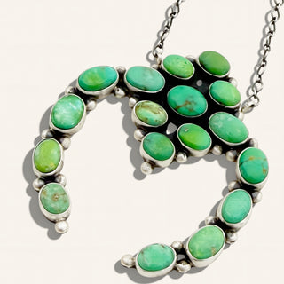 Necklace with green gemstones and silver accents on a light background