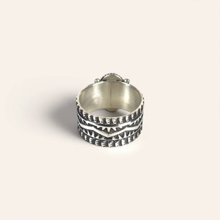 Silver ring with textured design on a light gray background