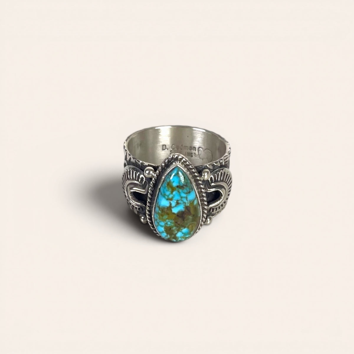 Silver ring with a turquoise stone on a beige background