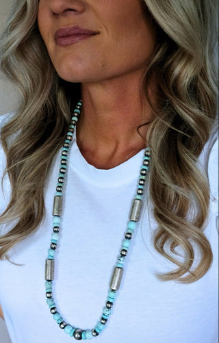 Woman wearing a long beaded necklace with a neutral background