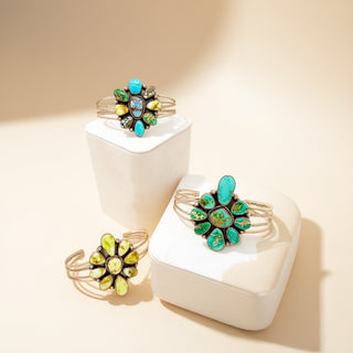 Three silver cuffs with various stones on a beige background