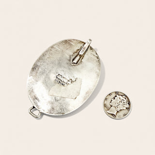 Silver pendant and coin on a beige background
