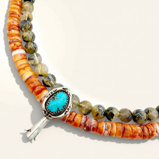 Beaded bracelet with a turquoise stone and silver clasp on a beige background