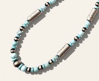 Necklace with turquoise beads and silver accents on a light background