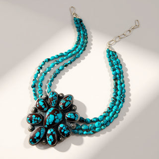 turquoise beaded necklace with turquoise flower pendant on a beige background