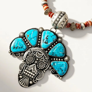 skull pendant with turquoise stones on a beige background