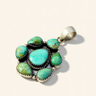 Turquoise stone pendant with silver setting on a beige background