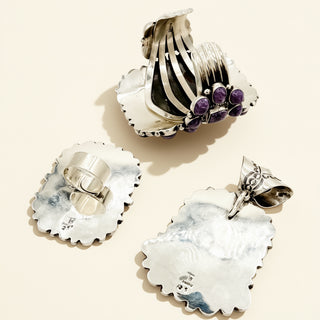 Silver jewelry set with shell-like designs on a beige background