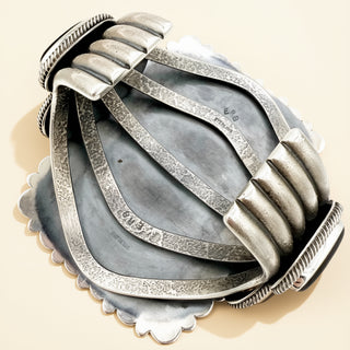 Silver bracelet with textured design on a beige background