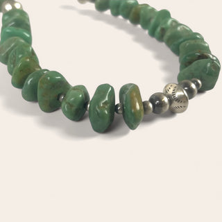 Necklace with green beads and silver accents on a white background