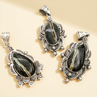 Three silver pendants with black stones on a beige background