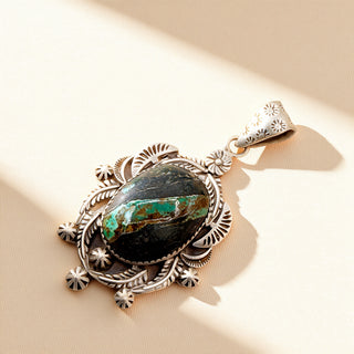 Silver pendant with black stone on a beige background