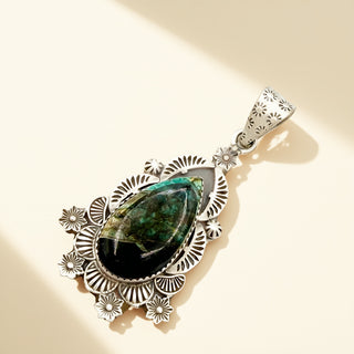 Silver pendant on a black stone with a beige background