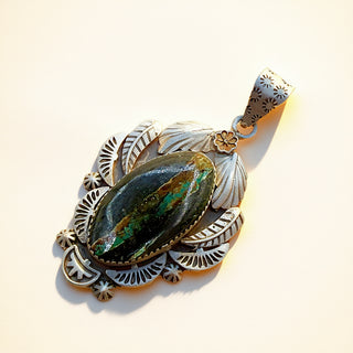 Silver pendant with a black stone on a beige background