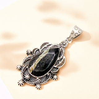 Silver pendant with a black stone on a beige background