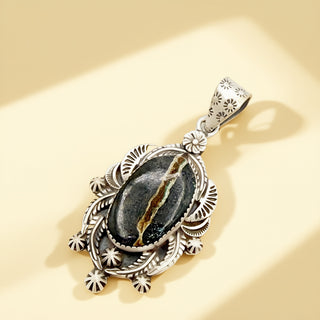 Silver pendant with black stone on a beige background