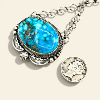 Necklace with blue stone and coin pendant on a beige background